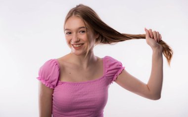 Uzun sarı saçlarını çeken tatlı bir genç kadın. Güzel bir kadın beyaz arka plan fotokopi alanında saç tutuyor. Kafa ve saç bakım ve sağlık konsepti