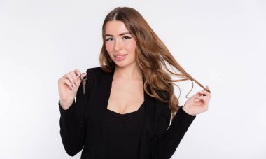 Kendi iş konseptini açmak. Elinde ev anahtarı olan gülümseyen bir iş kadını ya da yeni evin anahtarlarını gösteren bir emlakçı, beyaz arka planda izole edilmiş.