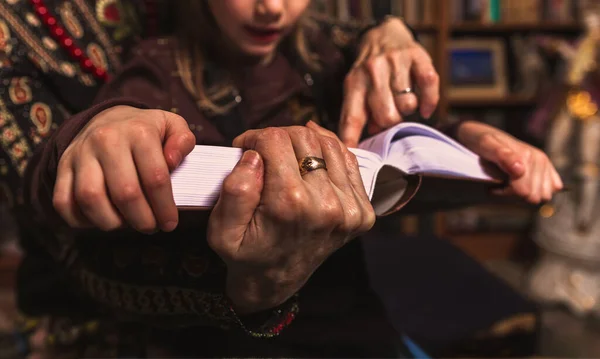 祖母和孙女在家里的图书馆读了一本大书 把老手和小孩手拉手拉在一起 手拿着一本书 家庭舒适 业余爱好教育和经验 — 图库照片