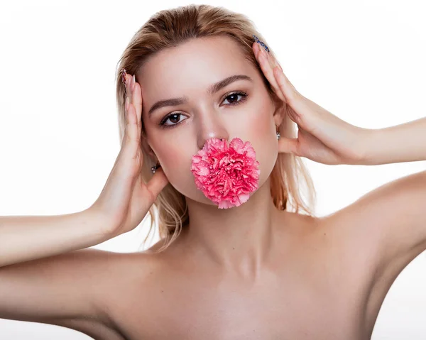 口の中にピンクの花を持つ魅力的な若い女性 白の背景にピンクの花を持つブロンドモデル 美と医療の概念テキストのためのフリースペース — ストック写真