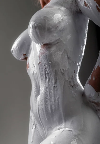 艺术裸体女人涂满了油漆 穿着白色油漆的裸体女人摆出一副雕塑的模样 在灰蒙蒙的背景下缓缓地沿着身体流下 — 图库照片