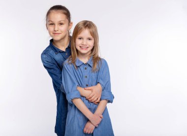 İki mutlu arkadaş ya da kız kardeş sarılıyor. Birlikte eğlenmek ve beyaz arka planda duygusal pozlar vermek, mutlu bir gülümseme, arkadaşlık ve ilişki tarzı insanlar kavramı.