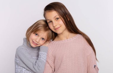En iyi arkadaşlar ya da kız kardeşler birlikte mutlular. Birbirlerine yakın duruyorlar. Arkadaşlarının omuzlarında dinleniyorlar. Gülümseyen kızlar örgü kazak giyer ve arkadaşının omzuna yaslanır.