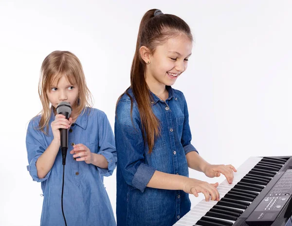 Music lesson. Two child girls in music school learning to play the piano and sing on white background