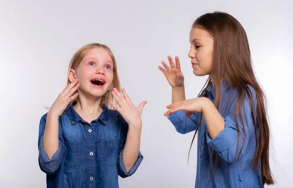 He cries with happiness. Girl consoling her crying friend by blowing air on her and soothes. Two girls, one with tears in her eyes and the other comforting her friend standing on white background