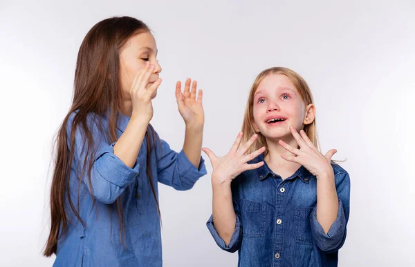 He cries with happiness. Girl consoling her crying friend by blowing air on her and soothes. Two girls, one with tears in her eyes and the other comforting her friend standing on white background