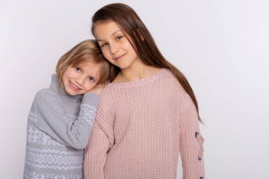 En iyi arkadaşlar ya da kız kardeşler birlikte mutlular. Birbirlerine yakın duruyorlar. Arkadaşlarının omuzlarında dinleniyorlar. Gülümseyen kızlar örgü kazak giyer ve arkadaşının omzuna yaslanır.