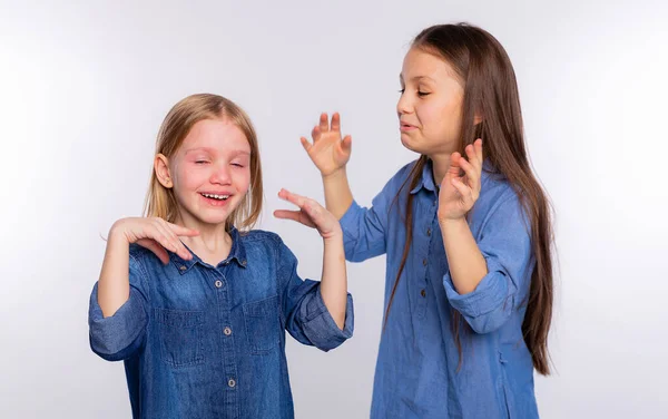 He cries with happiness. Girl consoling her crying friend by blowing air on her and soothes. Two girls, one with tears in her eyes and the other comforting her friend standing on white background