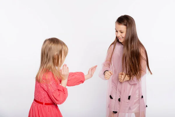 Best friends girls fight. Two young girls wear pink dress having fun and playful quarrel trying to repeat the techniques of karate on white background