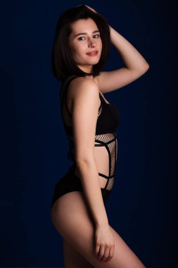 Baştan çıkarıcı siyah iç çamaşırlı bir kadın. Çekici güzel bayan iç çamaşırı reklamcısı koyu mavi arka planda ince beden metin için boş alan.