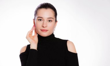 Kısa saçlı ve temiz tenli bir kadın. Yüzü yakın, teni bronzlaşmış, siyah balıkçı yakalı güzel bir kadın beyaz arka planda.