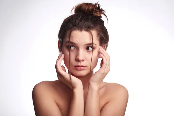 Young woman problem skin. Acne, pimple, clear and clean, oily, dry skin concept. Cose up of worried young lady touching her face gently on white background