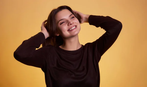 若いブルネットの女性が黄色の背景スタジオの肖像画に隔離されたポーズでセーターを着た 人々の誠実な感情ライフスタイルの概念 モックアップコピースペース — ストック写真