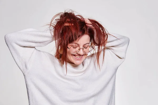 Smiling redhead woman in big eyeglasses with pierced tunnel in ears posing over white background copy space
