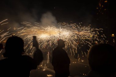 Barselona, Katalonya İspanya - 24.09.2021: Geleneksel yangın gösterisi, ünlü Fiestas de Gracia 'nın finali, yerel halk ve turistler için favori eğlence merkezi. İnsanlar şeytan gibi giyinip havai fişek attılar.