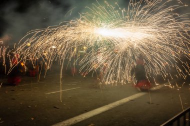 Barselona, Katalonya İspanya - 24.09.2021: Geleneksel yangın gösterisi, ünlü Fiestas de Gracia 'nın finali, yerel halk ve turistler için favori eğlence merkezi. İnsanlar şeytan gibi giyinip havai fişek attılar.