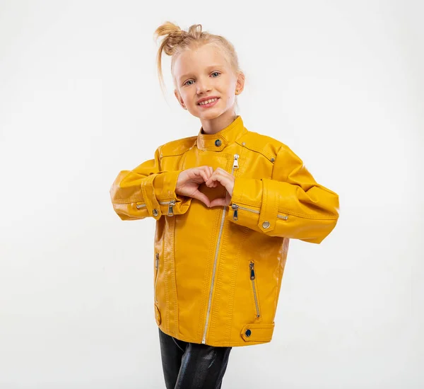 Pretty Blonde Little Girl Shows Heart Hands Leather Mustard Jacket — Fotografia de Stock