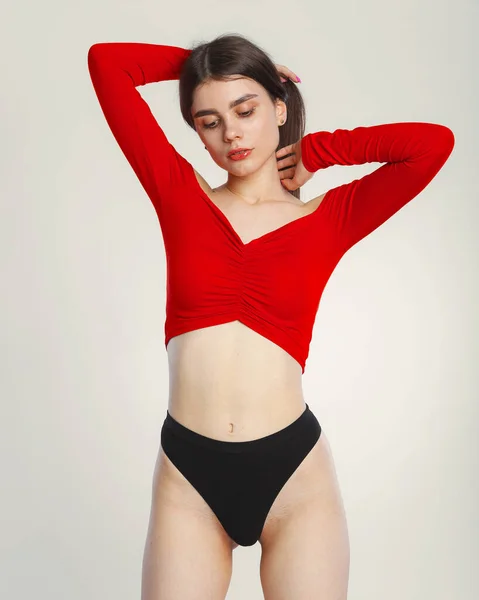 Jonge Vrouw Poseren Een Rood Shirt Zwart Slipje Grijze Achtergrond — Stockfoto