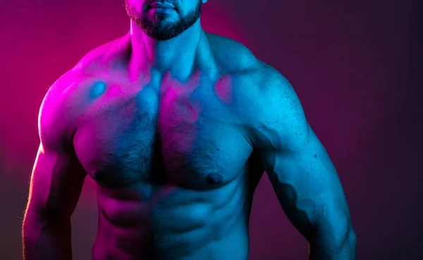 身强体壮的男人正站在五颜六色的霓虹灯下 裸露着肌肉 胸部和腹部肌肉在霓虹灯下 — 图库照片