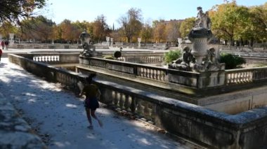 Jardins de la Fontaine, 1745 yılında Fransa 'nın Provence şehrinde inşa edilen La Fontaine Bahçeleri' nde spor için koşan genç bir kız. Roma binalarının ve heykellerin kalıntıları, klasik tarz, Jardins de la Fontaine