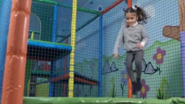 Kız, çocuk eğlence merkezinde trambolinde zıplıyor. Trambolin eğlence merkezi. Oyun odası