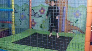 Oyun merkezinde trambolinde zıplayan 6 yaşında bir çocuk.