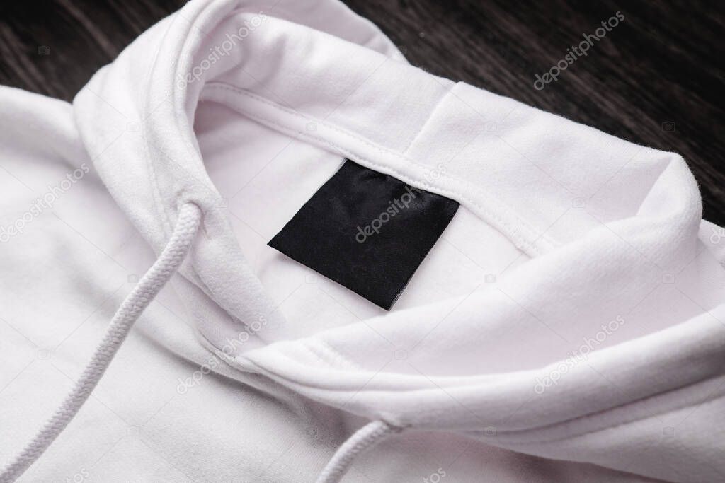 Blank clothing label on the texture of a white sweater hoodie. Label with empty space for text. Clothing and brand concept.