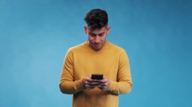 İzole bir zeminde duran bir adam cep telefonunu yazarken ve kullanırken.