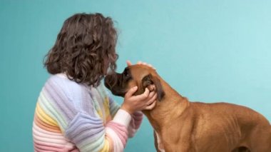Kadın boksör köpeğini okşuyor ve ona sarılıyor..