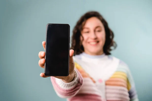 Frau zeigt Smartphone mit leerem Bildschirm vor Kamera, während sie vor isoliertem Hintergrund steht. — Stockfoto