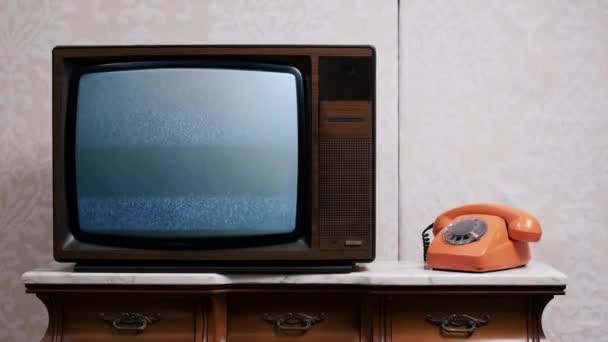 Старе телебачення без сигналу і статичного впливу на екран зі старим телефоном на старовинному наборі — стокове відео