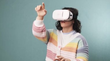 VR kulaklık takan bir kadın izole bir arka planda sanal gerçekliği tecrübe ediyor. Yavaş çekim videosu. Teknoloji ve yenilik kavramı.