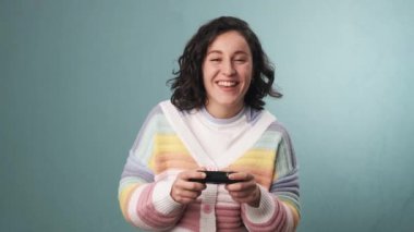 Bir kadının, izole bir arka planda elinde joystick ile oyun oynarken eğlenmesini yavaş çekimde izlemek. Teknoloji ve eğlence konsepti.