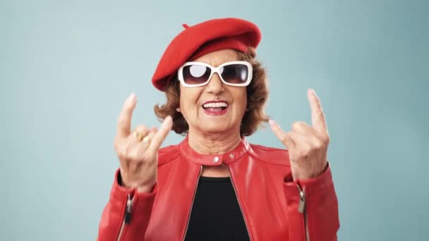 Happy Senior Female Trendy Red Jacket Hat Sunglasses Gesturing Horns — Stockvideo