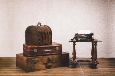 View of a stack of old vintage suitcases and an old typewriter on a table. Retro style concept.