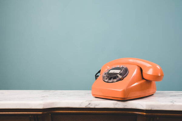 Крупный план старого оранжевого телефона на столе с копировальным местом. Концепция коммуникации и ретро стиля.