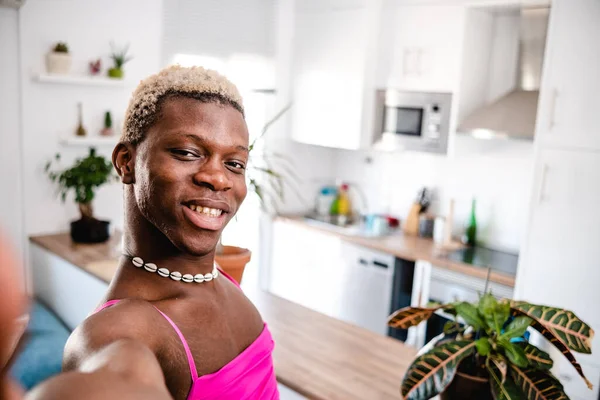 Modern mutfakta selfie çekerken gülümseyen ve kameraya bakan kısa saçlı Afro-Amerikan transseksüel erkek.