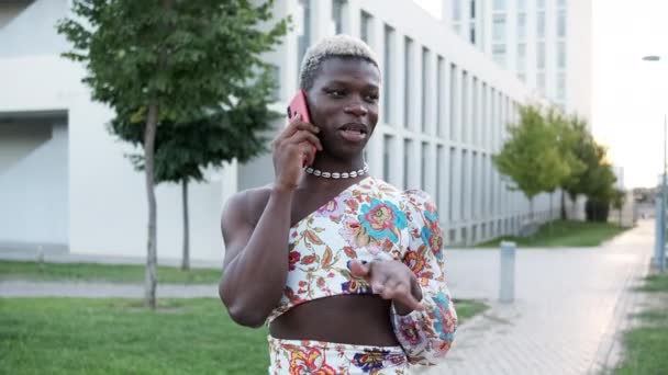 跟踪拍摄非洲黑人穿着时髦服装在城市公园走路时摆出姿势和在手机上说话的照片 — 图库视频影像