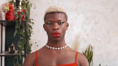 Boyalı saçlı, şık makyajlı, gündüzleri kameraya bakan Afro-Amerikan transseksüel model.