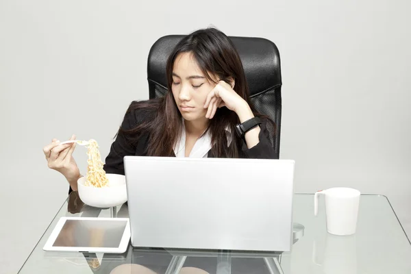 Nő munkavállaló egészségtelen étel elfogyasztása közben hivatal óra. — Stock Fotó
