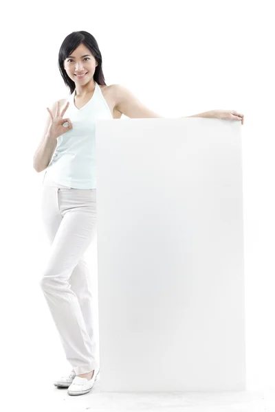 Mulher casual em pé atrás de uma placa em branco no fundo branco (conceito verde ) — Fotografia de Stock