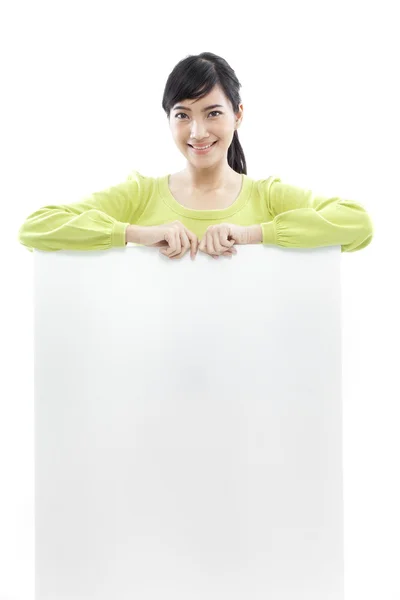 Casual woman standing behind a blank board on white background (green concept) — Stock Photo, Image