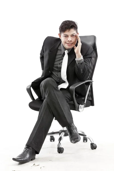 Young businessman sitting on chair, against white background — Stock Photo, Image