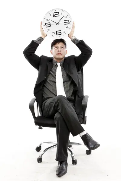 Portret van een zakenman zitten en houden een klok tegen witte achtergrond — Stockfoto