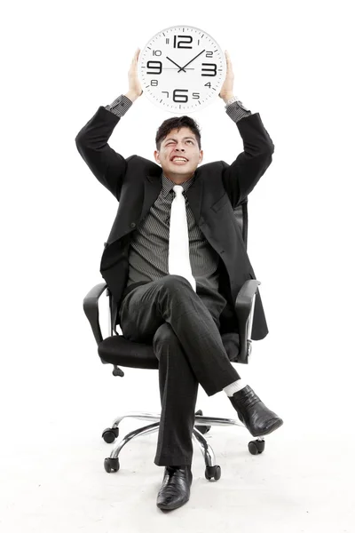 Retrato de un hombre de negocios sentado y sosteniendo un reloj sobre fondo blanco — Foto de Stock