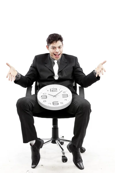 Retrato de un hombre de negocios sentado y poniendo un reloj entre su pierna y el fondo blanco — Foto de Stock