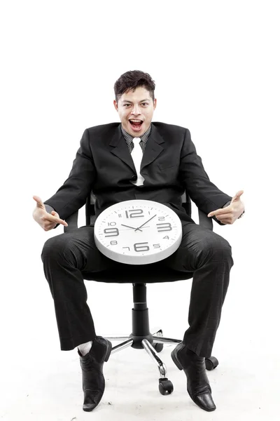 Retrato de un hombre de negocios sentado y poniendo un reloj entre su pierna y el fondo blanco — Foto de Stock