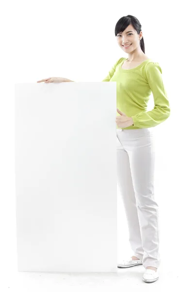 Casual woman standing behind a blank board on white background (green concept) Royalty Free Stock Images