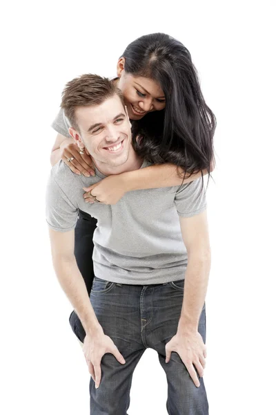 Portrait of a happy young man giving a piggyback ride to her girlfriend against white background — Stock Photo, Image