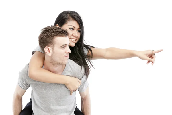 Portrait of a happy young man giving a piggyback ride to her girlfriend against white background — Stock Photo, Image